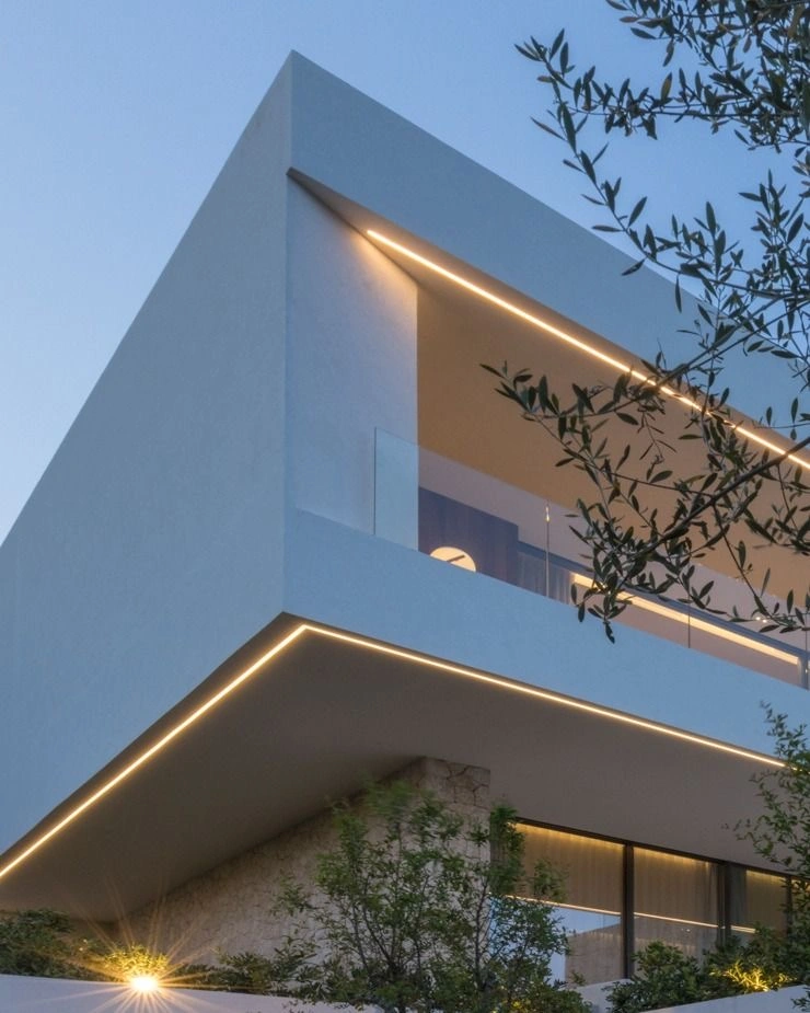 Fachada residencial al atardecer con líneas de luz cálida integradas en los volados